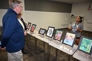 visitors observe student artwork at anthony middle school during school priority day.